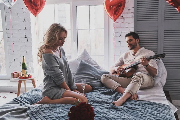 Bonito Jovem Tocando Guitarra Acústica Para Bela Namorada Enquanto Celebra — Fotografia de Stock