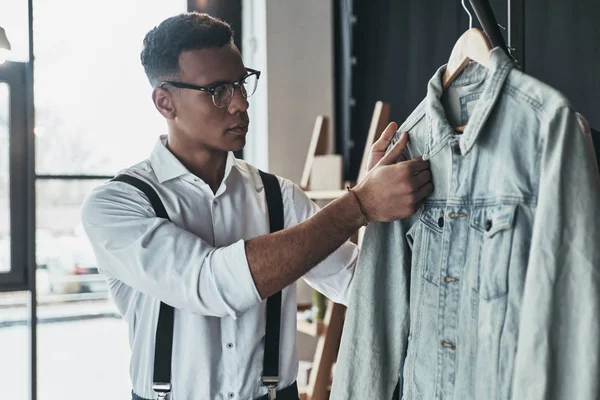 Bystrý Mladý Muž Dotýká Džínová Bunda Stoje Showroomu — Stock fotografie