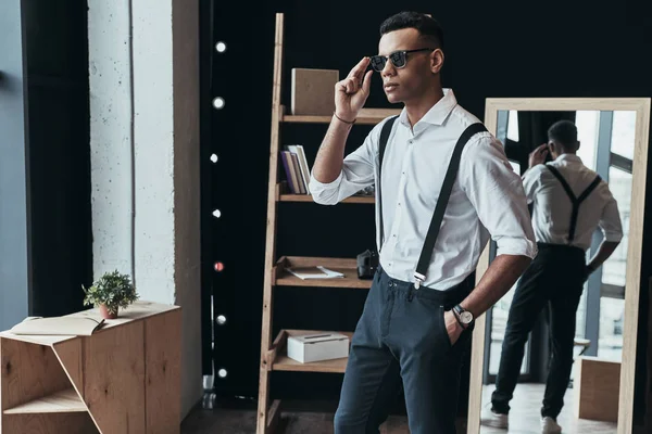 fashionable man looking through window and standing in fashion show room