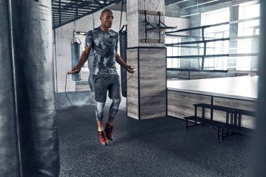 atlama ipi ile spor salonunda egzersiz yaparken erkeklik Afrikalı adamın tam uzunlukta