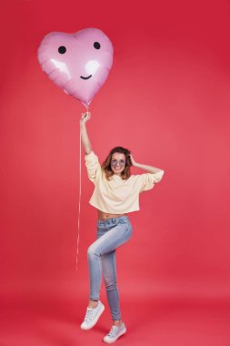 kalp tutan çekici genç gülümseyen kadın şeklinde balon ve el saç duran pembe bir arka plan karşı koruma