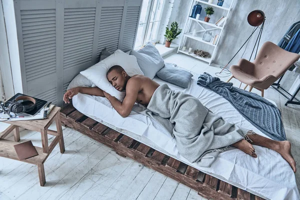 handsome African man sleeping in bed at home