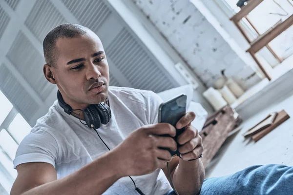 Bello Giovane Africano Che Naviga Smartphone Casa Cuffie Sul Collo — Foto Stock