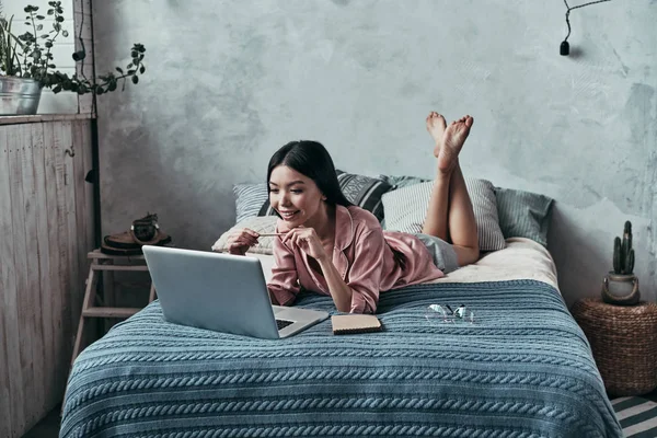 Luie Jonge Vrouw Met Behulp Van Computer Glimlachen Terwijl Liggend — Stockfoto