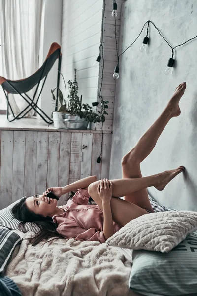 Feliz Asiático Jovem Mulher Falando Telefone Inteligente Enquanto Deitado Cama — Fotografia de Stock