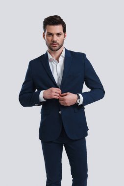 Ceketini ayarlama ve kamera Studio bakarak tam takım yakışıklı genç adam 