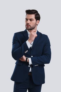 yakışıklı genç adam takım elbise uzak duran gri bir arka plana dayanır arıyor.