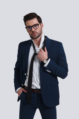 Kameraya bakarak ve onun kravat duran gri arka plan karşı kapalı alarak takım elbiseli genç adam bitkin