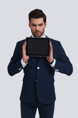 iyi tam takım dijital tablet tutan genç adam arıyorum ve gri arka plan karşı dururken kamera arıyorum