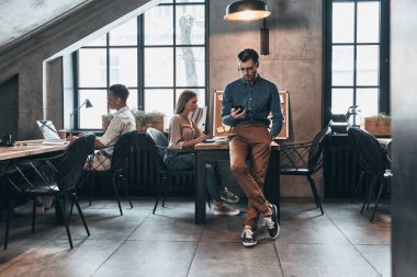 Office, dizüstü bilgisayarlar ile çalışan genç insanlar adam ayakta ve cep telefonu tarama  