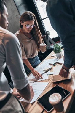 bir grup genç kendine güvenen insan içinde yazıhane kağıt belgeleri ile çalışırken iş toplantısı 