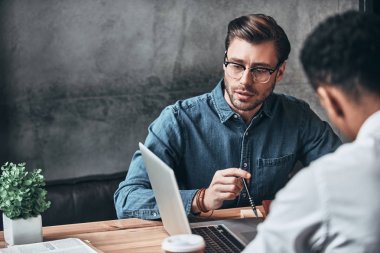 Akıllı rahat kıyafet laptop ile masada oturan genç modern erkeklerde 