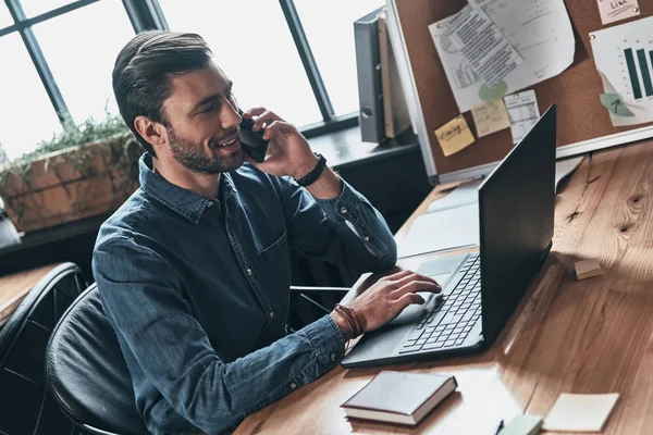 Sonriente Joven Guapo Hablando Teléfono Inteligente Uso Computadora Portátil Mientras — Foto de Stock