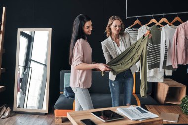 satış temsilcisi kadın moda butik çalışırken müşteri için kıyafet seçmek için yardımcı