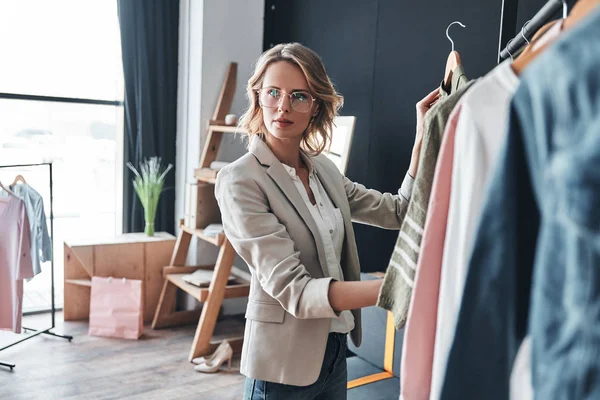 Blonde Woman Choosing Clothes Rank While Standing Workshop — Stock Photo, Image