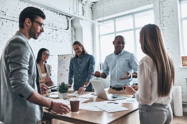 bir grup genç insan iş yönetim kurulu odasında dururken tartışıyor