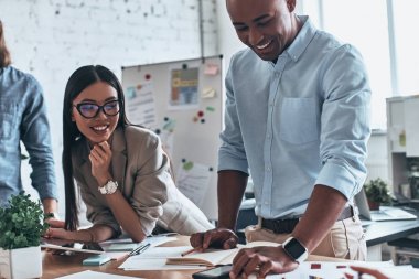 Birlikte çalışmak için çok mutluyum. Gruba birlikte iletişim ve yönetim kurulu odasında çalışırken gülümseyen genç modern