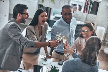 Kutlama. Birbirimizi toasting ve yönetim kurulu odasında dururken gülümseyen genç iş adamları Üstten Görünüm