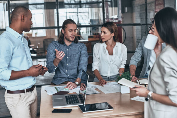 Thinking about every detail. Group of young business people communicating while working in the office