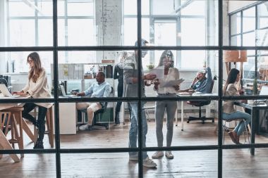 Ekibi iş başında. Çalışma ve birlikte yönetim kurulu odasında cam duvarın arkasında dururken iletişim modern gençlerin tam uzunlukta