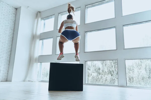 ジムでエクササイズをしながらジャンプ スポーツ服の若い女性の背面図 — ストック写真