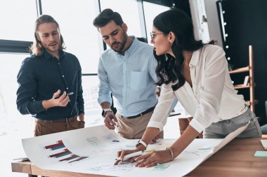 Şimdiye kadar en iyi takım. Grup ofis planı ile çalışan kadın ise bir şey tartışırken kendine güvenen genç iş adamları
