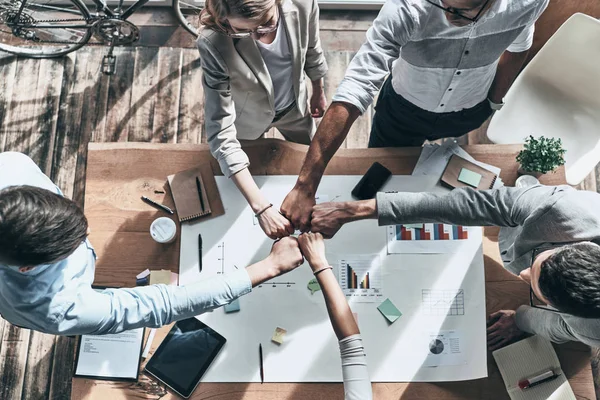 Bovenaanzicht Van Collega Vuisten Bijeen Houden Boven Tabel Met Blauwdruk — Stockfoto