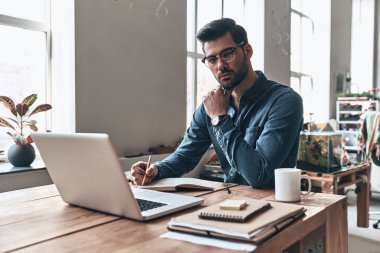 düşünme ve laptop ile masada oturan yakışıklı delikanlı