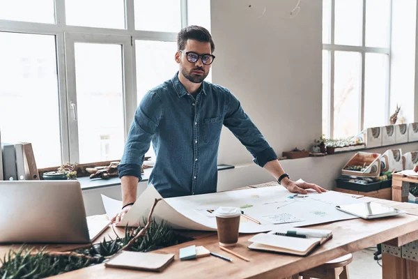 architect man working in creative working space with blueprint on table