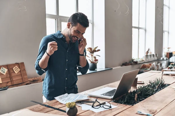 Jovem Bonito Feliz Falando Telefone Inteligente Enquanto Está Mesa Madeira — Fotografia de Stock