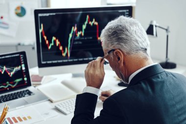 Ofiste çalışırken bilgisayar kullanarak şık bir iş elbisesi giyen kıdemli tüccarın üst dikiz görüntüsü.