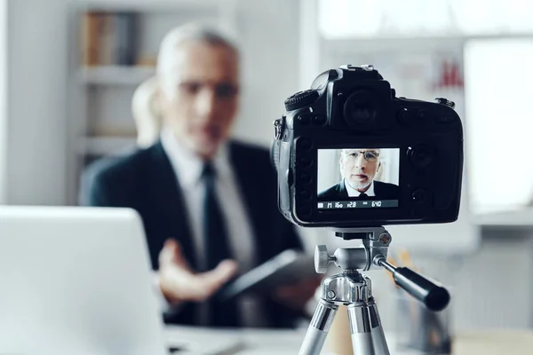 Ανώτερος άνθρωπος με κομψό κοστούμι επιχειρήσεων χρησιμοποιώντας ψηφιακή ταμπλέτα, ενώ κάνοντας βίντεο κοινωνικών μέσων μαζικής ενημέρωσης — Φωτογραφία Αρχείου