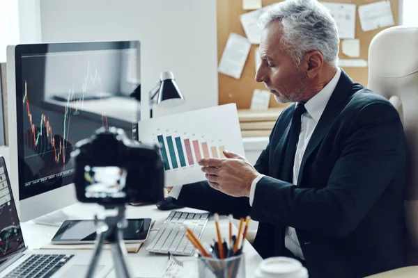 Senior homme en costume d'affaires élégant montrant graphique tout en faisant de la vidéo sur les médias sociaux — Photo