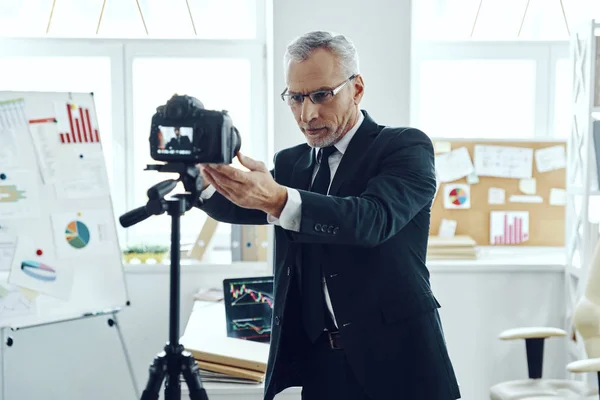 Hombre mayor en elegante traje de negocios ajustando la cámara de video mientras hace video de redes sociales —  Fotos de Stock