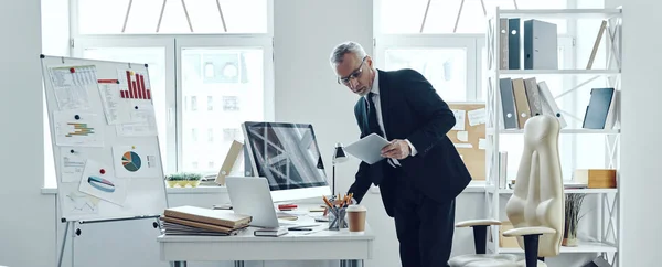 Longitud completa del comerciante senior en traje de negocios elegante usando tableta digital mientras trabaja en la oficina — Foto de Stock