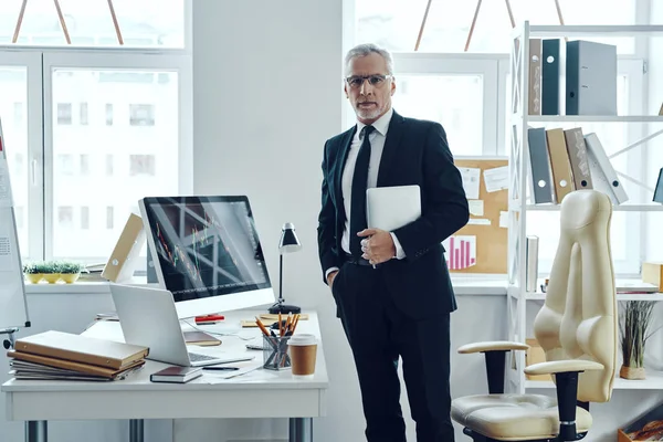 Starszy przedsiębiorca w eleganckim garniturze biznesowym korzystający z tabletu cyfrowego podczas pracy w biurze — Zdjęcie stockowe