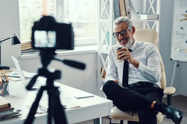 Šťastný dospělý muž v elegantní košili a kravatu říká něco a usmívá se, zatímco sociální média videa — Stock fotografie