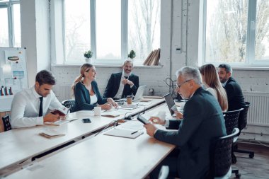 Modern teknolojileri kullanarak ve ofiste çalışırken bir şeyleri tartışarak şık kıyafet işçileri            