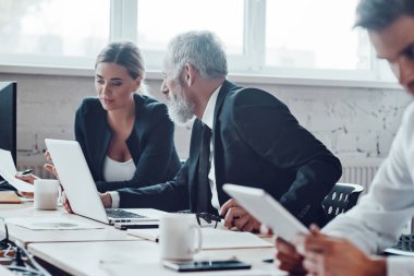 Konsantre meslektaşlar modern ofiste çalışırken personel toplantısı yapıyorlar.