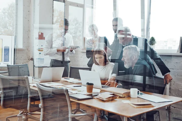 Self-motivated business team analyzing sales using modern technologies while having staff meeting in the board room