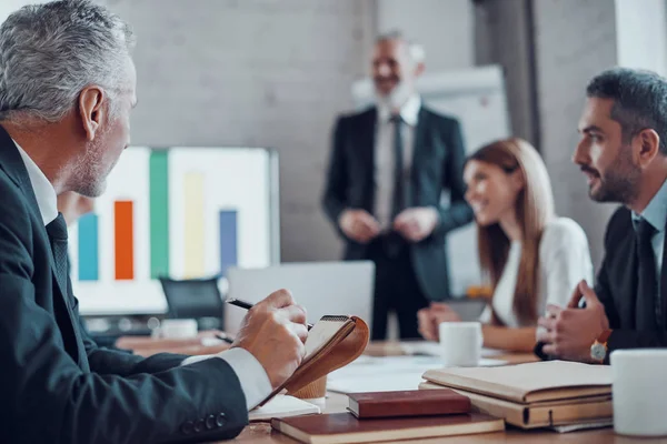 Volwassen Zakenman Schrijft Iets Terwijl Hij Samenwerkt Met Collega Bestuurskamer — Stockfoto