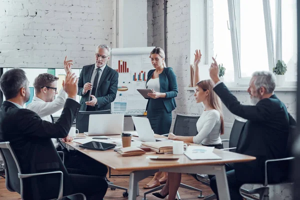 Successful business professionals voting with show of hands while working together in the modern office