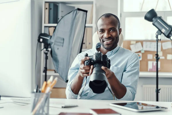 Guapo Joven Africano Sosteniendo Cámara Digital Sonriendo Mientras Trabaja Oficina — Foto de Stock