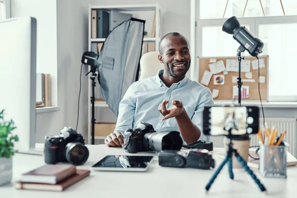 幸せな若いアフリカ人男性のシャツにデジタルカメラを示し ソーシャルメディアビデオを作りながら何かを伝える — ストック写真