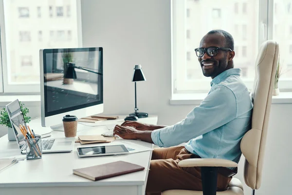 Ευτυχισμένος Νεαρός Αφρικανός Πουκάμισο Χρησιμοποιώντας Υπολογιστή Και Χαμογελώντας Ενώ Εργάζεται — Φωτογραφία Αρχείου