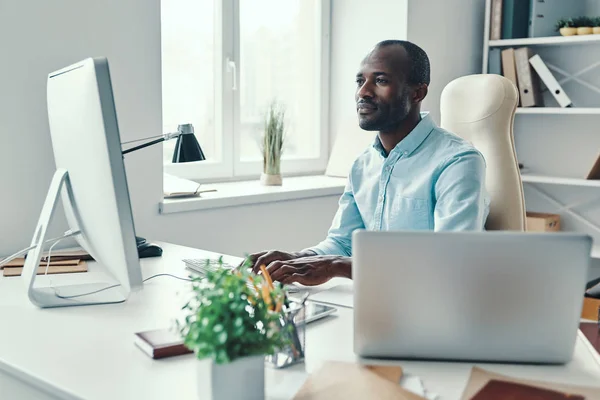 Hombre Africano Joven Concentrado Camisa Usando Computadora Mientras Trabaja Oficina — Foto de Stock