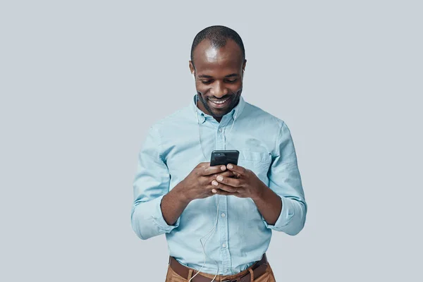 Jovem Africano Feliz Ouvindo Música Usando Smartphone Sorrindo Enquanto Está — Fotografia de Stock