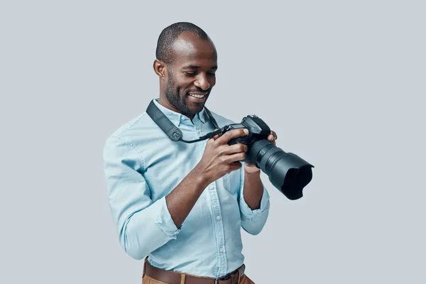 Szczęśliwy Młody Afrykanin Pomocą Aparatu Cyfrowego Uśmiecha Się Stojąc Szarym — Zdjęcie stockowe