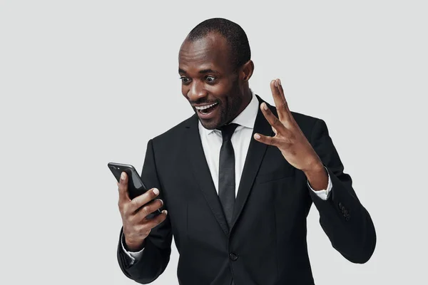 Sorprendió Joven Africano Ropa Formal Usando Teléfono Inteligente Sonriendo Mientras —  Fotos de Stock