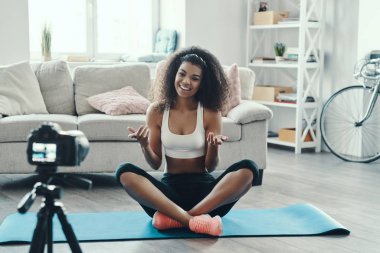 Sosyal medya videosu çekerken spor yapan ve gülümseyen güzel bir Afrikalı kadın.